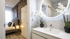 A modern bathroom with a large mirror, white sink, and potted orchids. - Skyline Lofts by LovelyStay (Matosinhos)