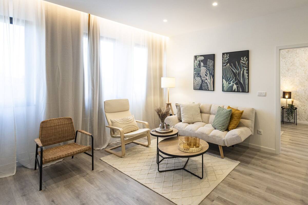 A modern living room with a sofa, armchairs, a coffee table, and a dining area.