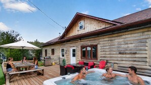 Una cabaña de madera con hidromasaje, mesa de picnic y zona de estar al aire libre.