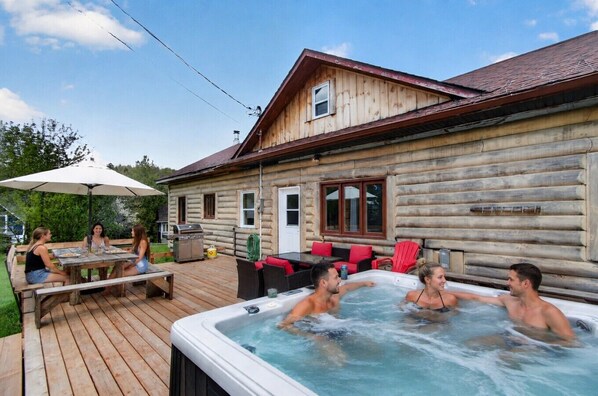 A wooden cabin with a hot tub, picnic table, and outdoor seating.