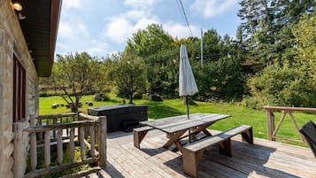 Enjoy al fresco dining on the deck with a barbecue grill and picnic table, surrounded by a lush lawn and beautiful trees.