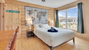Un dormitorio con cama, pared de madera con mapa mundial, ventana con cortinas y un letrero que dice "LA CAMÉLIA".