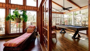A wooden room with a pool table, a lounge chair, and large windows. - Authentic Swiss Cabin - 4 BR with Hot Tub and pool table (Sainte-Agathe-des-Monts)