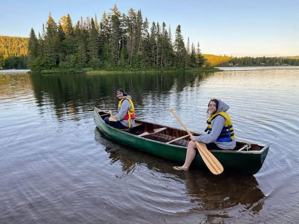 Two people in a canoe on a calm lake surrounded by trees.