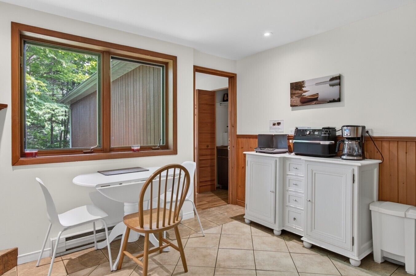 A small kitchen with a dining table, chairs, a coffee maker, and a cabinet.