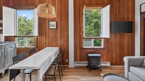 A room with wooden walls, a dining table, chairs, a fireplace, and a television. - Chalet Boréal, SPA, LAC & SKI (Saint-Donat-de-Montcalm)