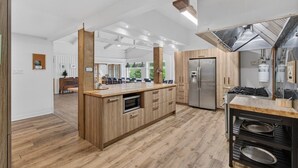 Una cocina moderna con una isla central, electrodomésticos de acero inoxidable y vista al comedor.