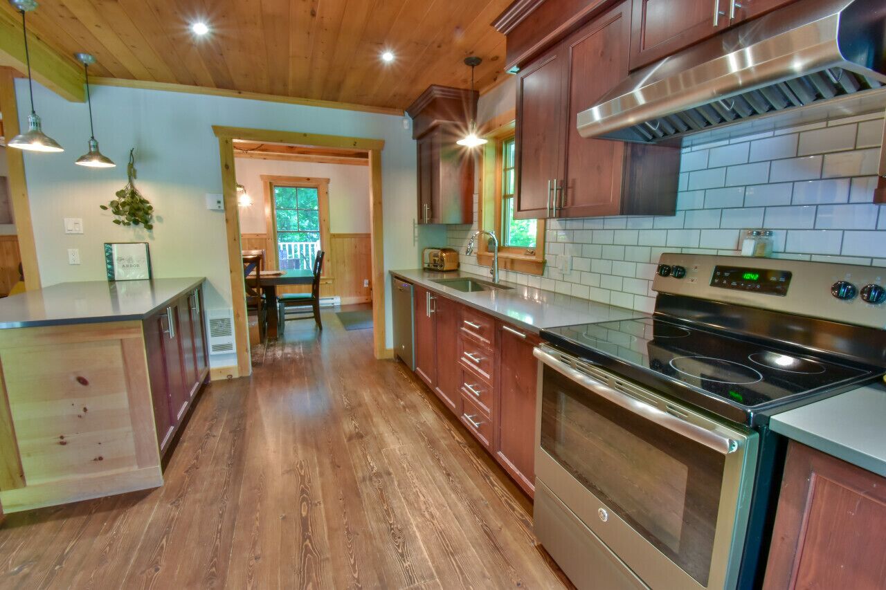 Een moderne keuken met houten kastjes, een roestvrijstalen fornuis en een betegelde spatwand.