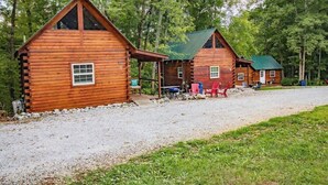 Une rangée de chalets en rondins, avec une allée en gravier et une pelouse devant.