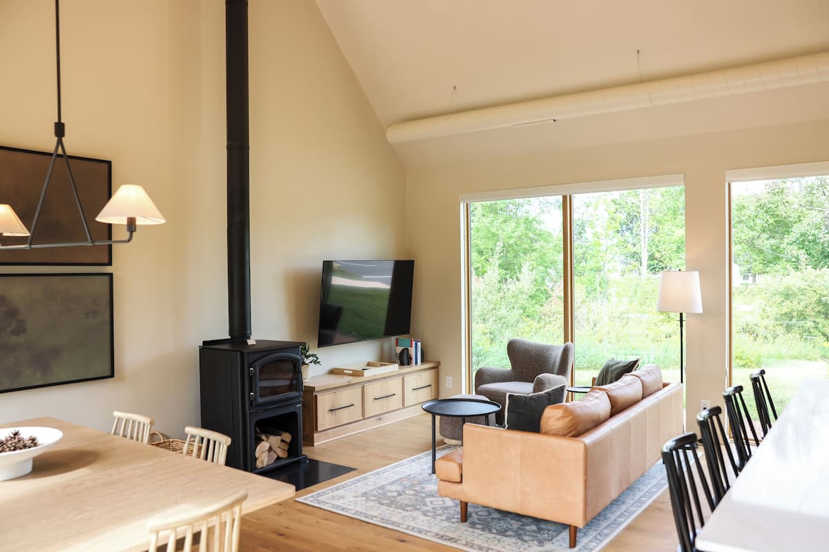 A modern living room with a fireplace, a flat-screen TV, a sofa, and a dining area.