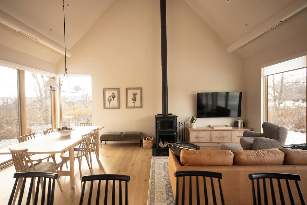 A spacious living room with a large wooden dining table, comfortable seating, a fireplace, and a television.