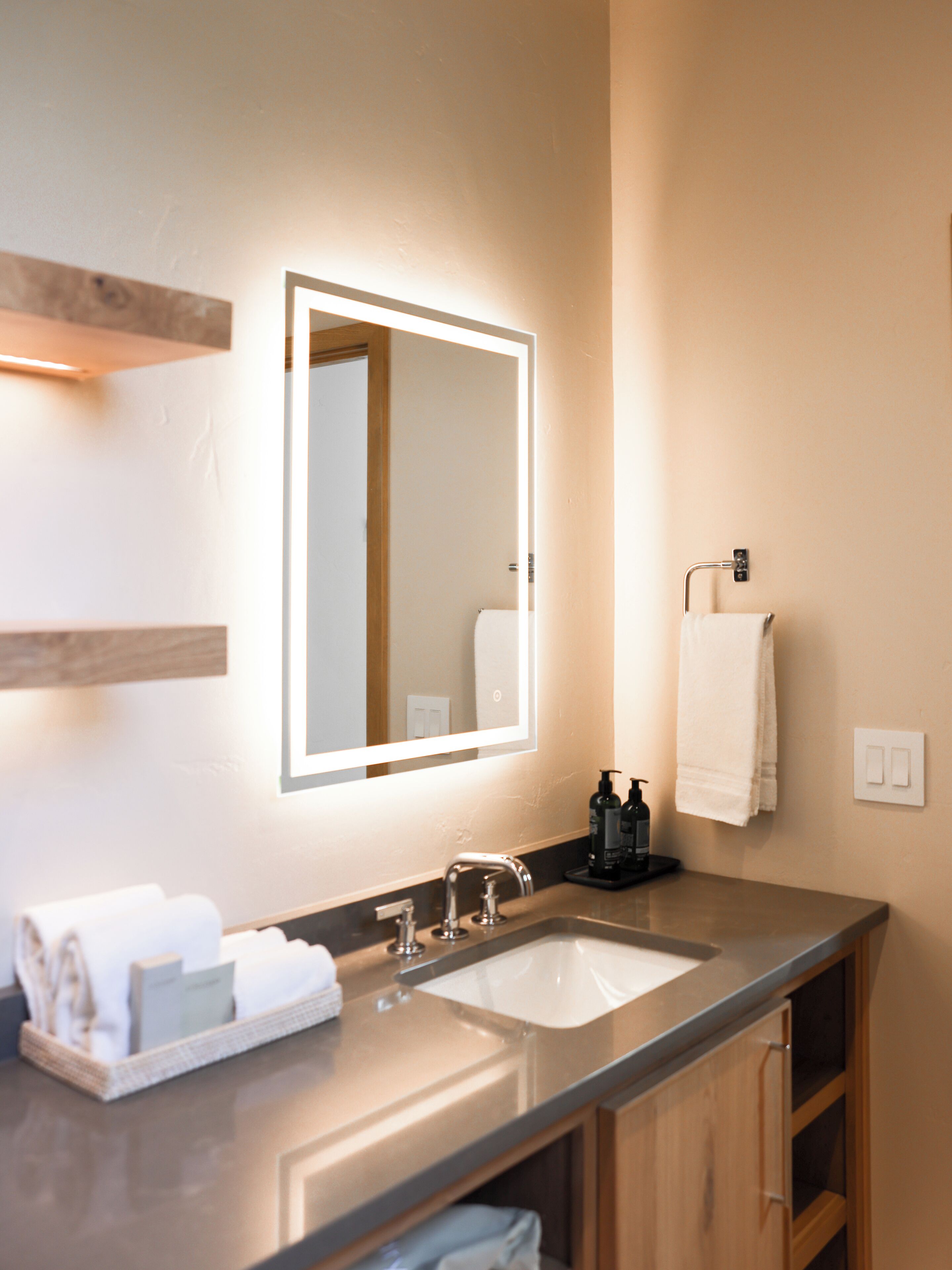 A modern bathroom with a large mirror, a sink, and a towel rack.