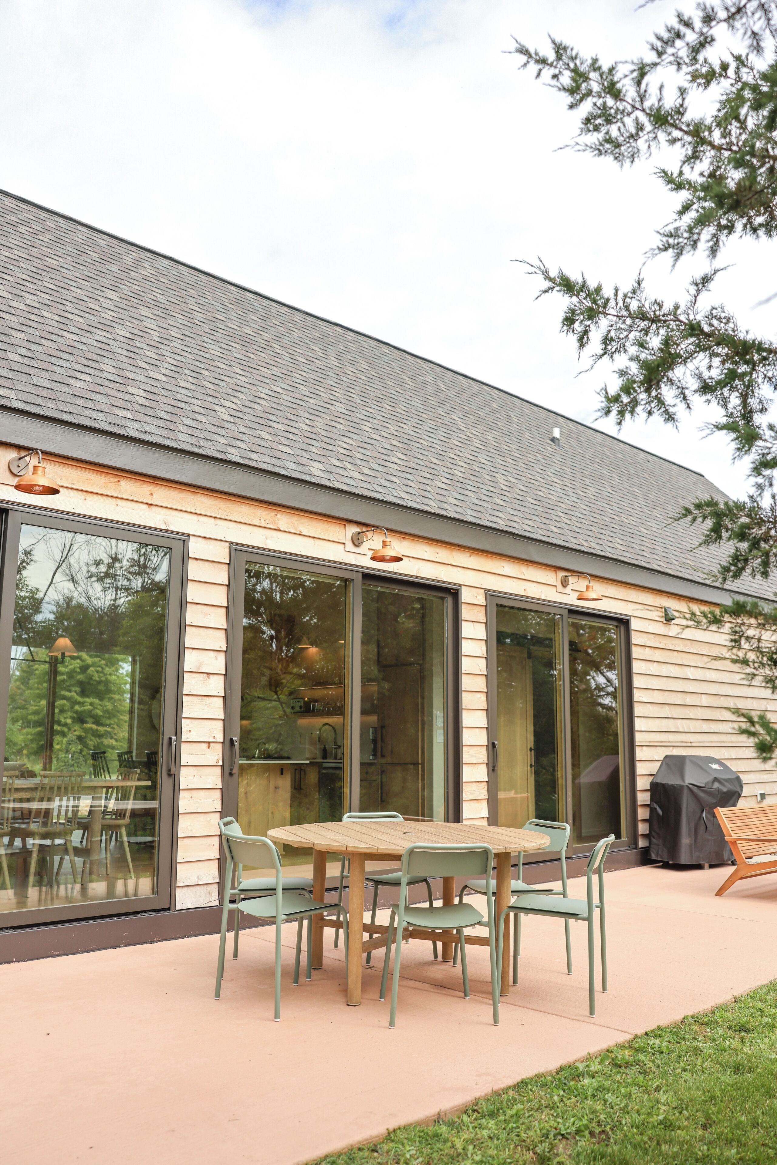 Een modern huis met een ruim terras, schuiframen en een barbecue.