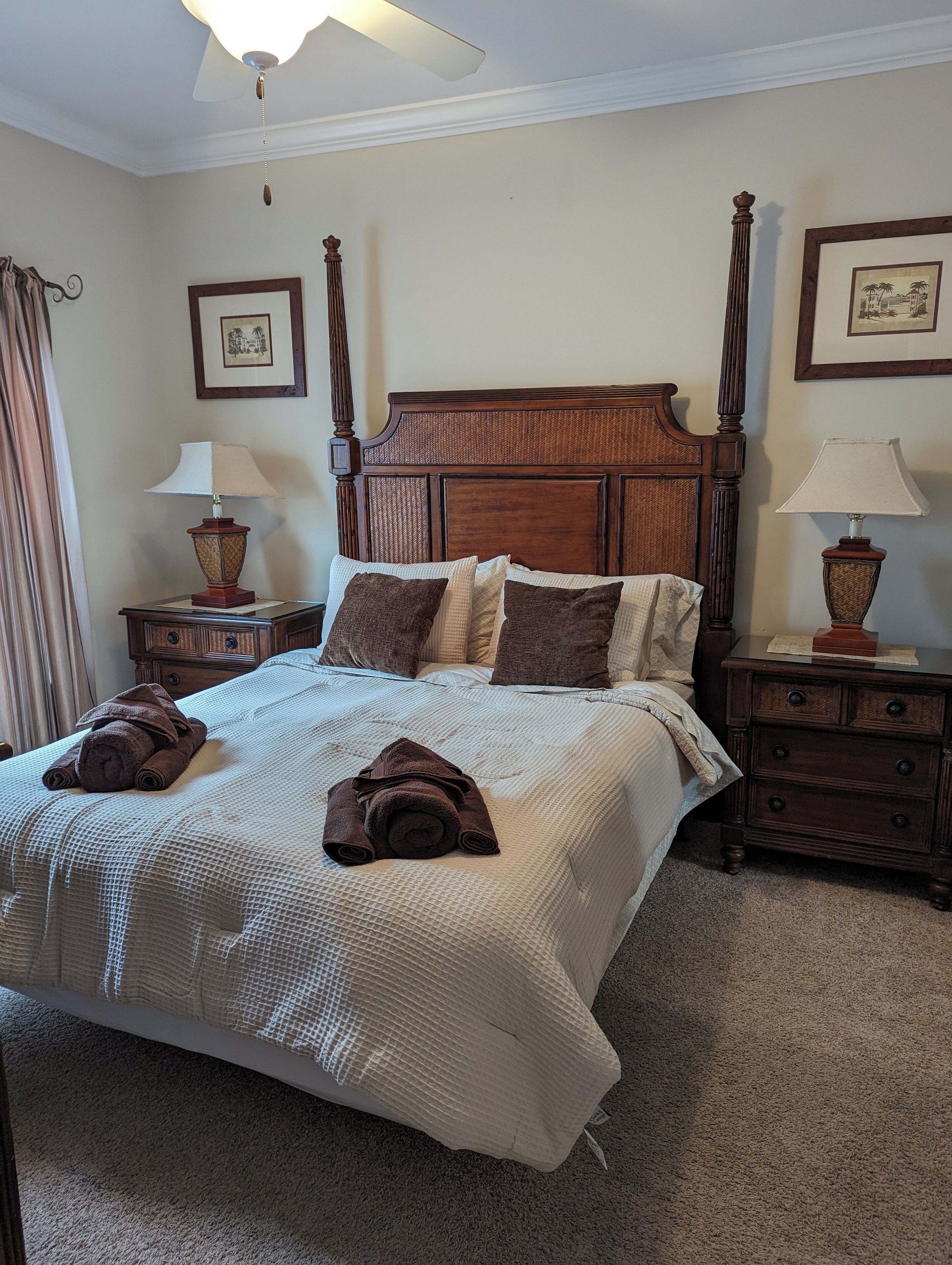 A neatly made bed with a textured white bedspread and brown pillows, flanked by wooden nightstands with lamps.