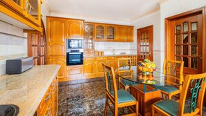 A kitchen with wooden cabinets, a glass dining table, and chairs. - Heatable Pool & BBQ Villa Near Albufeira Center (Albufeira)