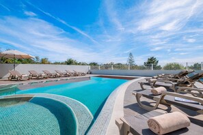 Une piscine avec des chaises longues et une pergola.
