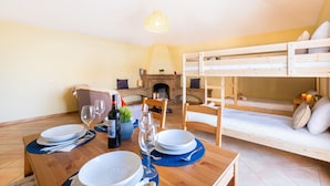 Ein gemütliches Zimmer mit Esstisch für zwei Personen, einem Stockbett und einem Kamin.