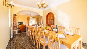 A dining area with a marble floor, wooden chairs, a wooden table set for four, and a chandelier.