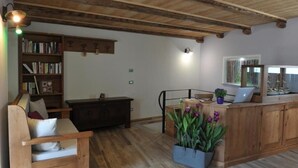 Una habitación acogedora con techo de madera, una estantería, un escritorio con una computadora portátil y una planta en maceta.