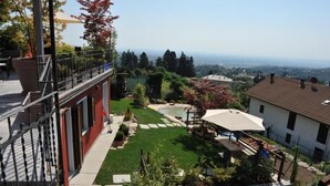 Una propiedad residencial con balcón, un pequeño jardín y vistas del paisaje circundante.
