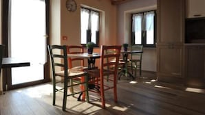 Un comedor con piso de madera, una mesa con sillas y una zona de cocina con armarios.