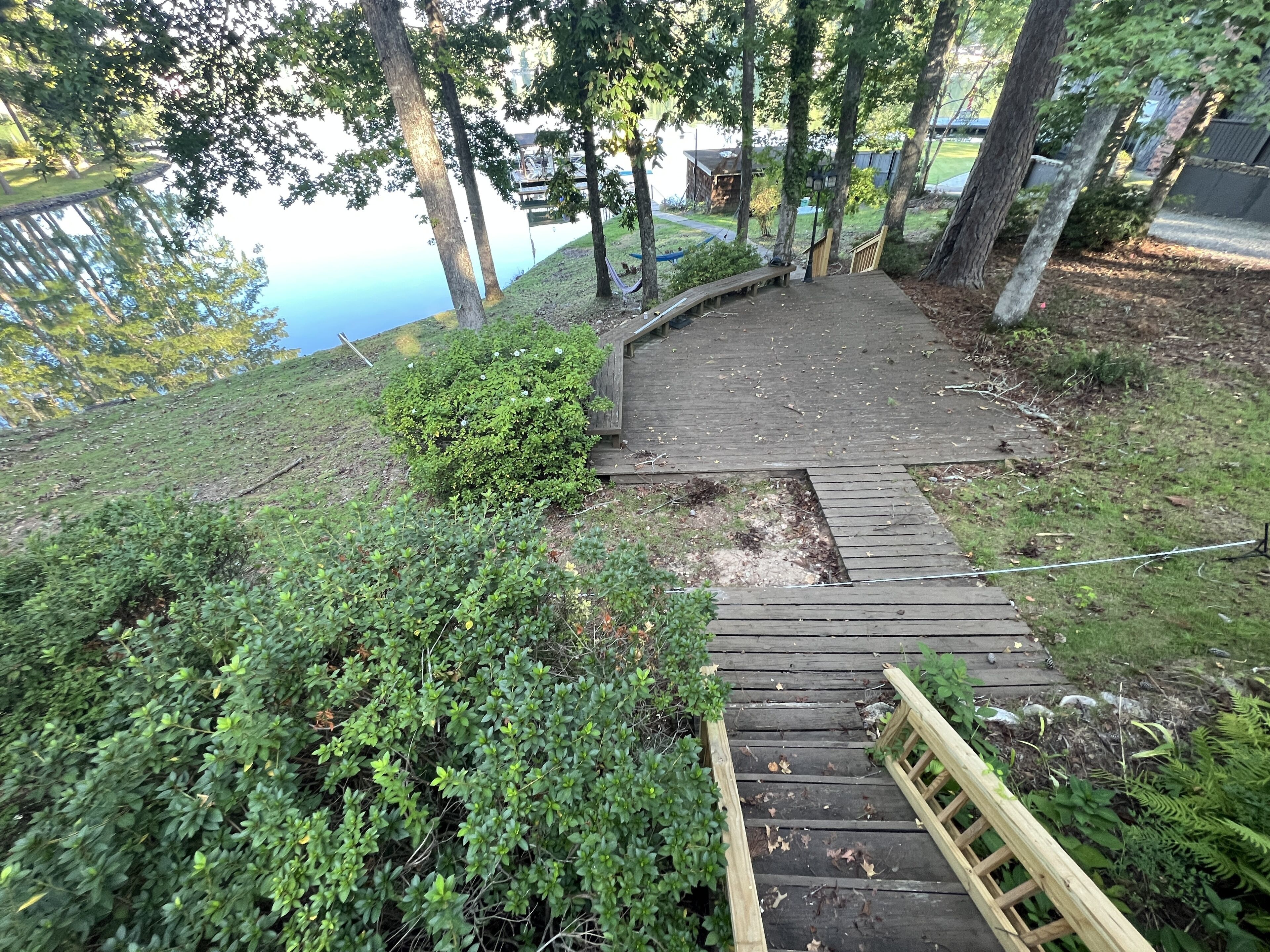 A wooden staircase leading up a hill with a view of a lake and a building in the background.