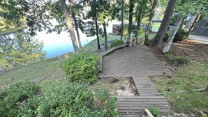 Una escalera de madera que sube una colina, con vista a un lago y un edificio al fondo.