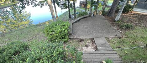 A wooden staircase leading up a hill with a view of a lake and a building in the background.