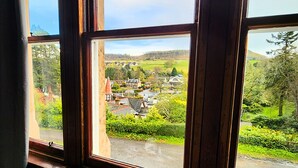 A view from a window with a cup on a table, overlooking a village with houses and greenery. - The Retreat Hotel  (Strathpeffer)