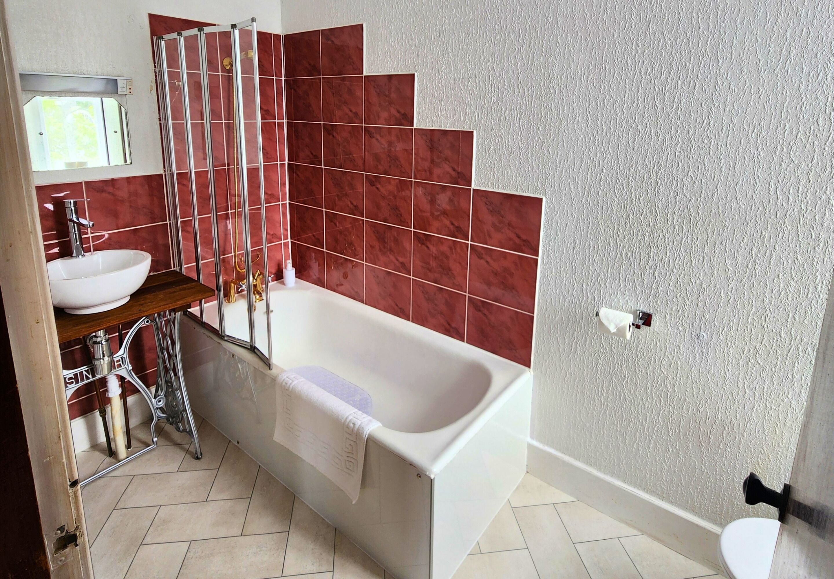 A bathroom with a white bathtub, a sink, and a shower.