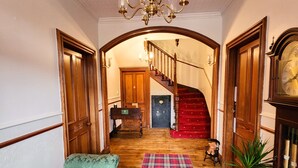 A wooden staircase leading to a room with a red carpet, a green upholstered chair, and a wooden door. - The Retreat Hotel  (Strathpeffer)