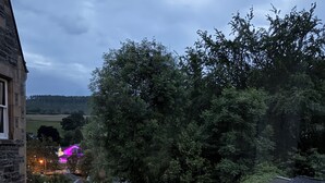 A patio area with wooden tables and benches, barrels, and string lights. - The Retreat Hotel  (Strathpeffer)