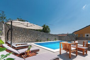 A swimming pool with lounge chairs and a stone wall. - Villa nona Andrejka (Vinodol)