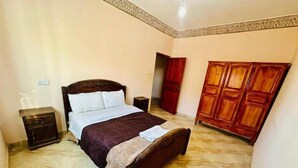 Een slaapkamer met een bed, nachtkastjes, een kledingkast en een deur.
