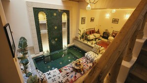 A pool area with a seating area, a decorative wall with intricate patterns, and a staircase leading to another level.