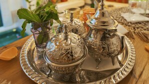 A dining table with a silver tray holding ornate silver teapots and a glass of water.