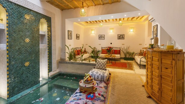 A spacious room with a pool, a wooden cabinet, and a sofa with cushions.