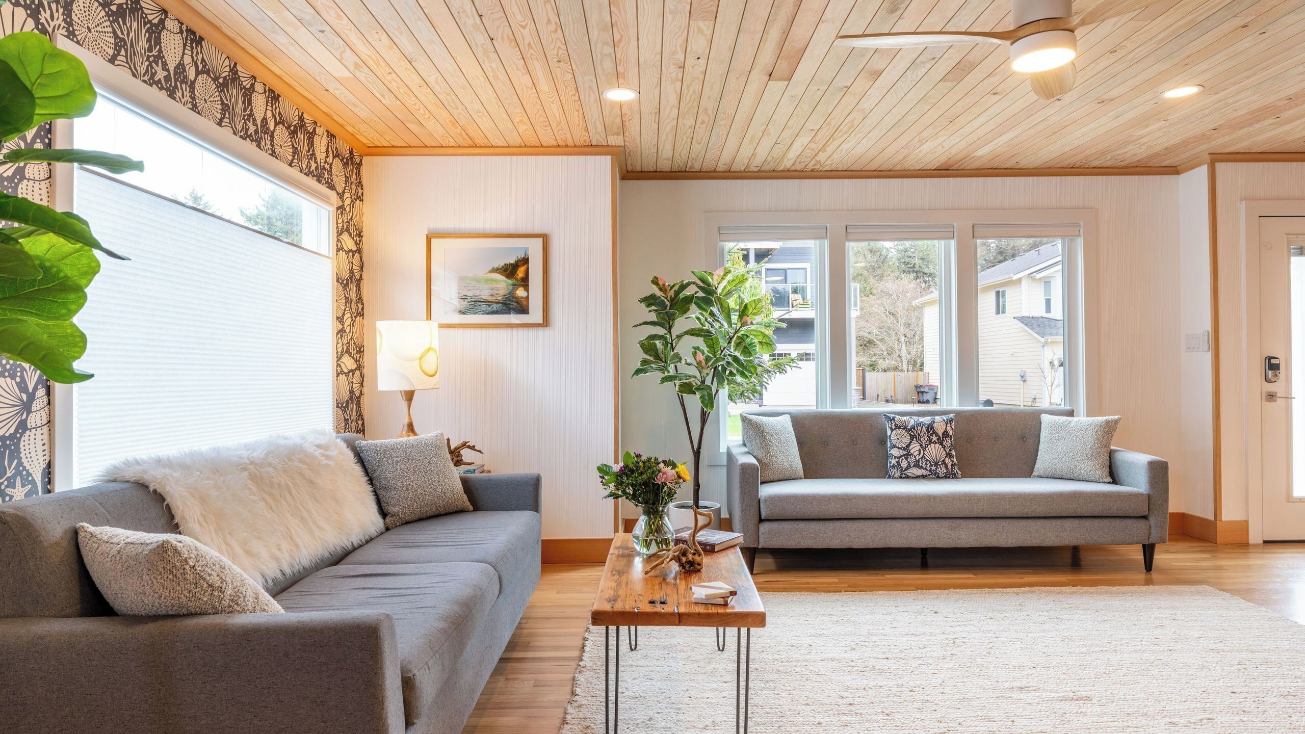 Ein Wohnzimmer mit zwei Sofas, einem Couchtisch, einer Lampe und einem großen Fenster.