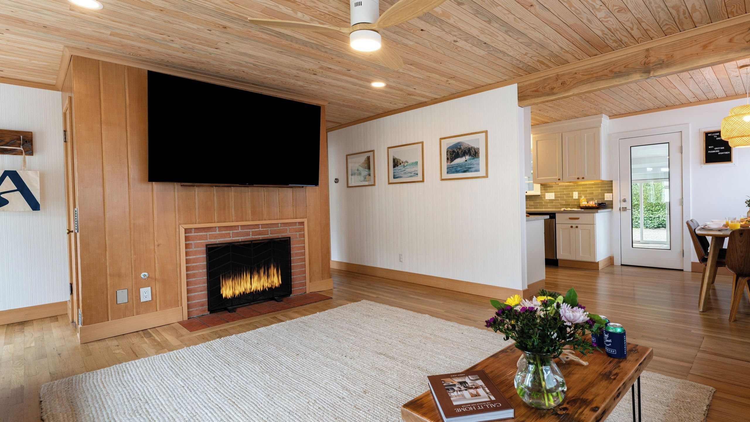 Een moderne woonkamer met een open haard, houten plafond en een flatscreen televisie erboven.