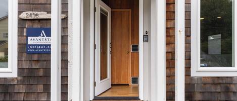 Entrada de una casa de madera con puerta, buzón y felpudo.