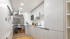 A modern kitchen with white cabinets, a stainless steel stove, and a wooden floor. - Prime Covent Garden gem with Air-Con (London)
