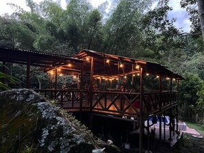 A wooden gazebo with string lights, surrounded by lush greenery. - Bahareque Hostal (Ibagué)