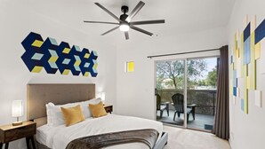 A modern bedroom with a large bed, a ceiling fan, and a view of the outdoors through a sliding glass door. - 2 mins 2 Mill Ave + ASU | Pool + EV Charging + GYM (Tempe)