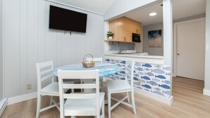 A dining area with a table, chairs, and a TV mounted on the wall.