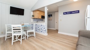 A modern kitchen with a flat-screen TV, wooden cabinets, and a blue and white backsplash.