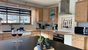 Una cocina moderna con armarios de madera, encimera negra y ventana con persianas.