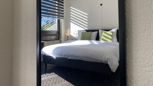Un dormitorio moderno con una cama grande, un radiador y una ventana con persianas.