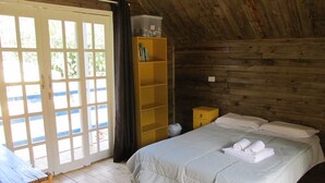 A wooden cabin room with a bed, a small table, and a bookshelf. - Beautiful chalet overlooking Pico do Marumbi (Morretes)