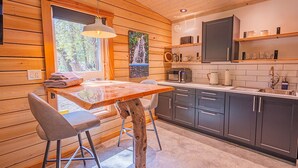 Una cocina moderna con paredes de madera, una mesa de comedor con sillas y un ventanal grande.