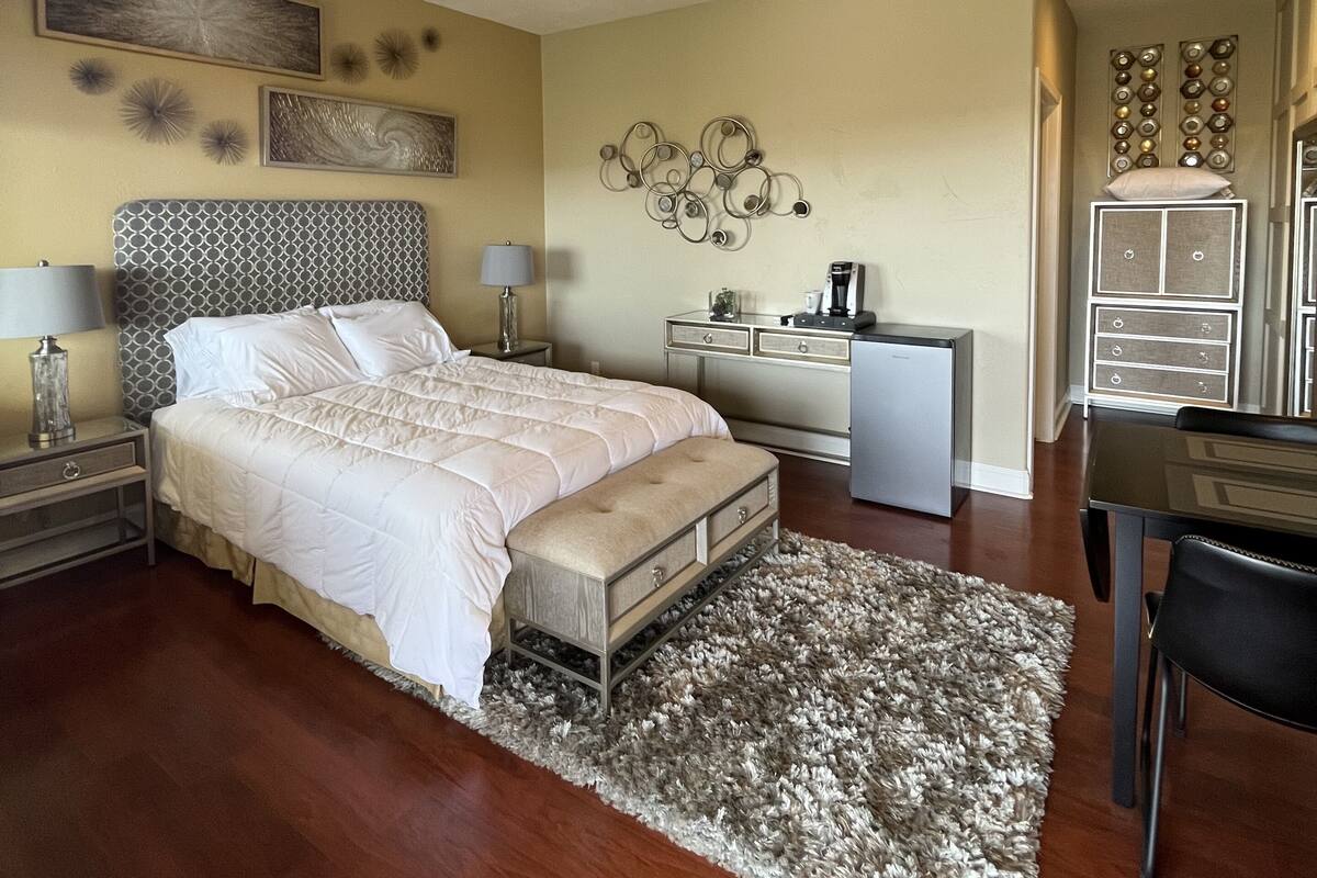 A bedroom with a bed, bedside tables, a desk, and a ceiling fan.